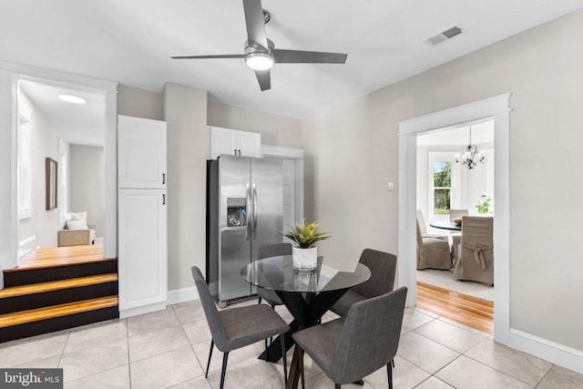 dining space featuring light hardwood / wood-style flooring and ceiling fan with notable chandelier