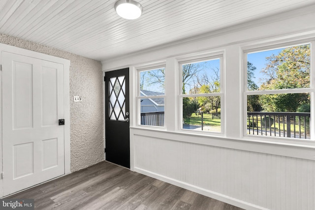 entrance foyer featuring dark wood-type flooring, wood ceiling, a healthy amount of sunlight, and wooden walls