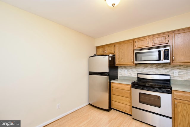 kitchen with light hardwood / wood-style floors, stainless steel appliances, and tasteful backsplash