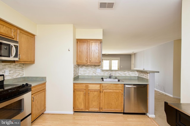 kitchen featuring light hardwood / wood-style floors, decorative backsplash, stainless steel appliances, and sink