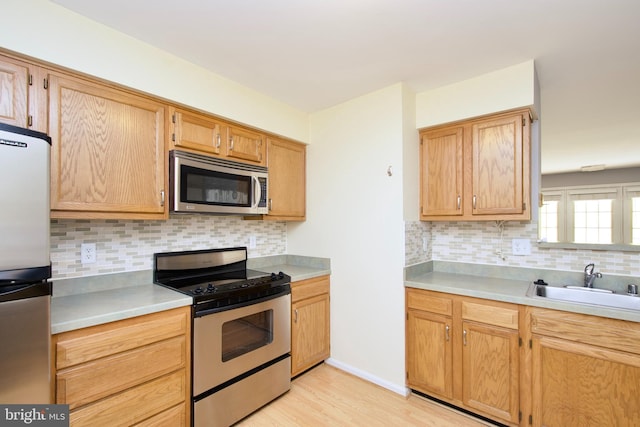 kitchen featuring sink, decorative backsplash, stainless steel appliances, and light hardwood / wood-style floors