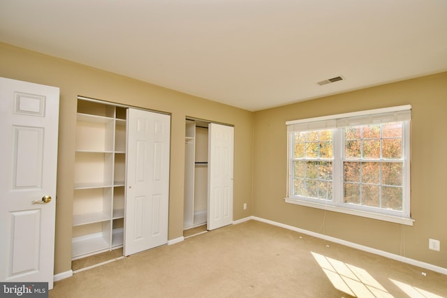 unfurnished bedroom with multiple closets and carpet floors