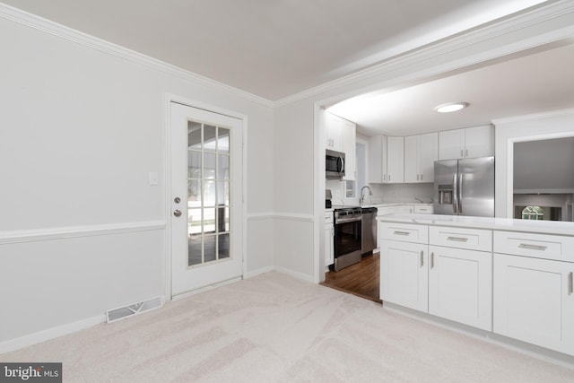 kitchen featuring appliances with stainless steel finishes, white cabinetry, and light colored carpet