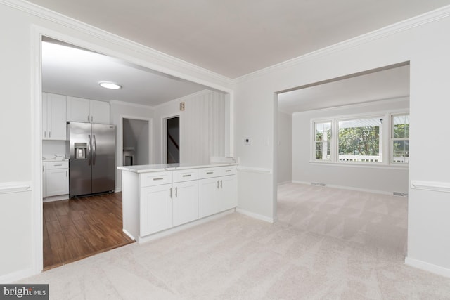 kitchen featuring ornamental molding, white cabinetry, stainless steel refrigerator with ice dispenser, and light colored carpet