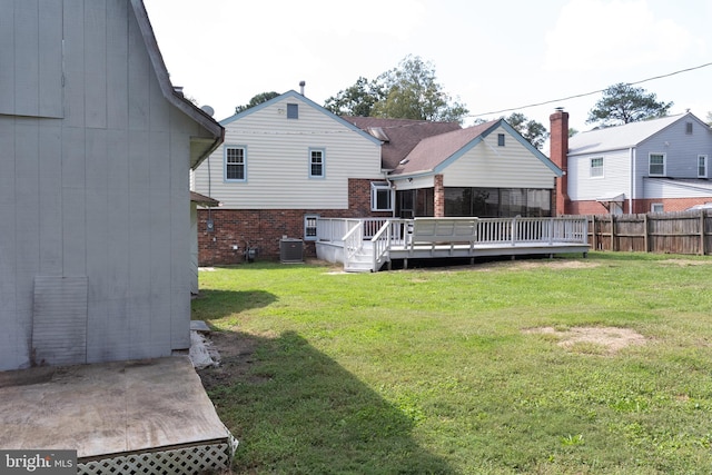 rear view of house featuring a wooden deck, a lawn, and central AC unit