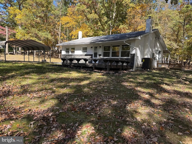 exterior space with a wooden deck, a lawn, and a carport