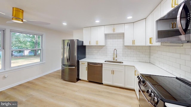 kitchen with decorative backsplash, white cabinetry, light hardwood / wood-style flooring, sink, and stainless steel appliances