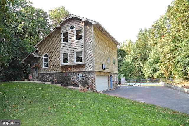 view of property exterior with a garage, a covered pool, and a yard