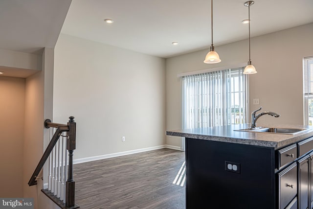 kitchen featuring an island with sink, hanging light fixtures, dark hardwood / wood-style floors, and sink