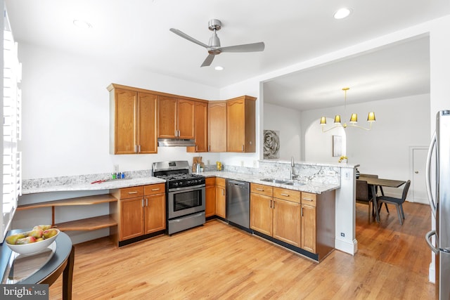 kitchen with hanging light fixtures, stainless steel appliances, kitchen peninsula, light wood-type flooring, and light stone counters