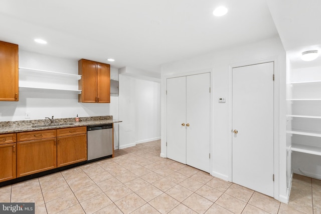 kitchen with stainless steel dishwasher, sink, light stone counters, and light tile patterned floors