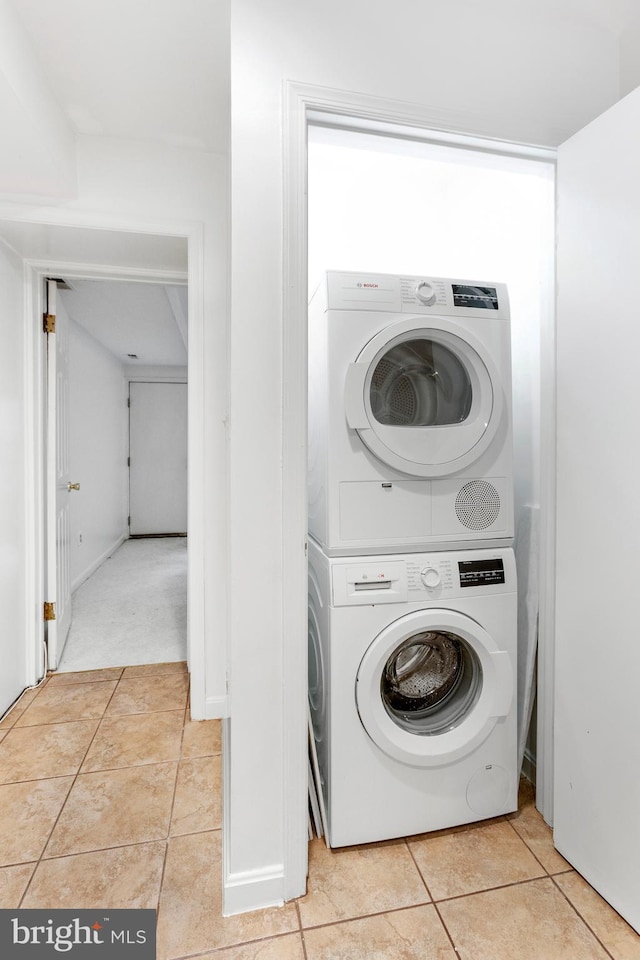 laundry area with stacked washer and dryer and light tile patterned floors