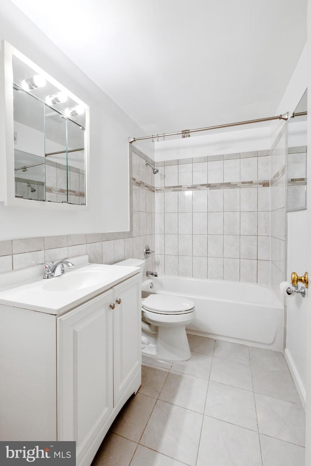 full bathroom with tiled shower / bath, tile walls, toilet, vanity, and tile patterned flooring