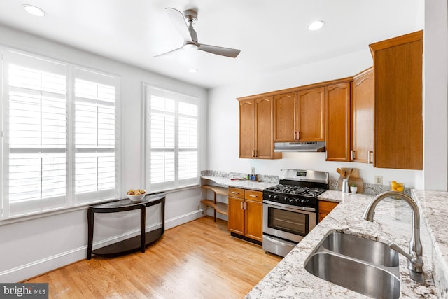 kitchen featuring stainless steel gas range, sink, light stone countertops, and light hardwood / wood-style floors