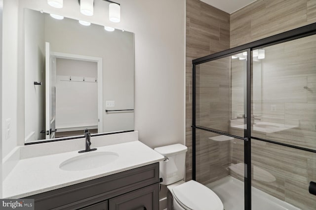 bathroom featuring toilet, an enclosed shower, and vanity