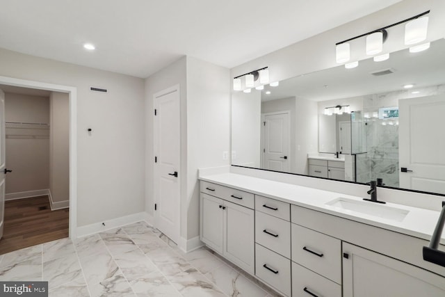 bathroom featuring a shower with shower door and vanity