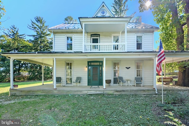 view of front facade with a front yard, a balcony, a porch, and a carport