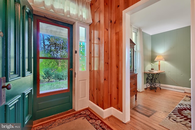 entryway with wood-type flooring, wooden walls, crown molding, and baseboard heating