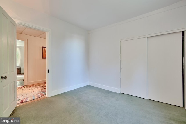 unfurnished bedroom featuring light carpet and a closet