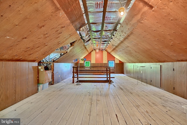 additional living space featuring lofted ceiling, wooden walls, and light hardwood / wood-style floors