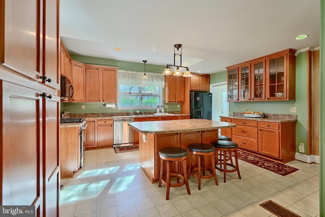 kitchen featuring a kitchen island, black appliances, a breakfast bar, hanging light fixtures, and light tile patterned floors