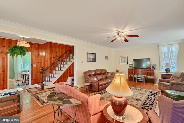 living room with wood walls, ornamental molding, hardwood / wood-style floors, and ceiling fan