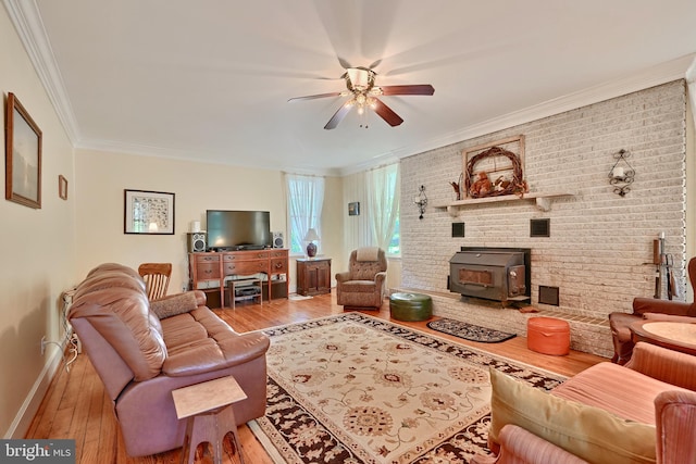 living room with ceiling fan, crown molding, hardwood / wood-style floors, and a wood stove