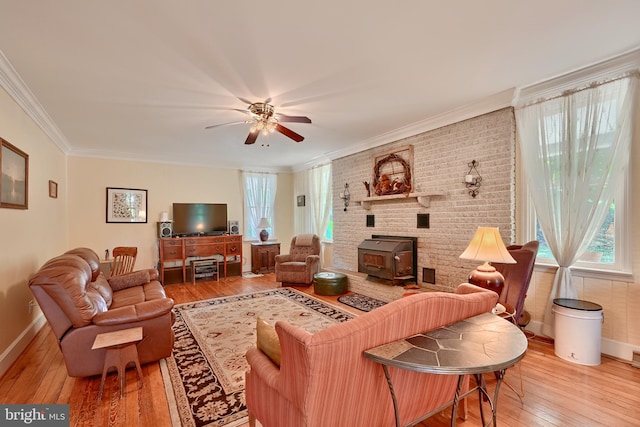 living room with wood-type flooring, ceiling fan, crown molding, and a wood stove