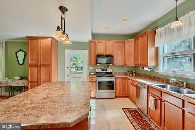 kitchen with stainless steel appliances, hanging light fixtures, sink, and a center island