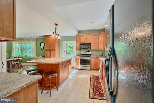 kitchen featuring pendant lighting, a wealth of natural light, a breakfast bar, and black appliances