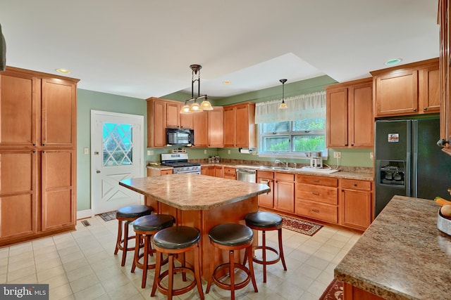 kitchen featuring hanging light fixtures, sink, a kitchen island, black appliances, and a kitchen breakfast bar