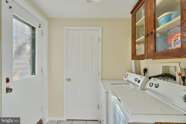 washroom with light tile patterned flooring, cabinets, and washer and clothes dryer