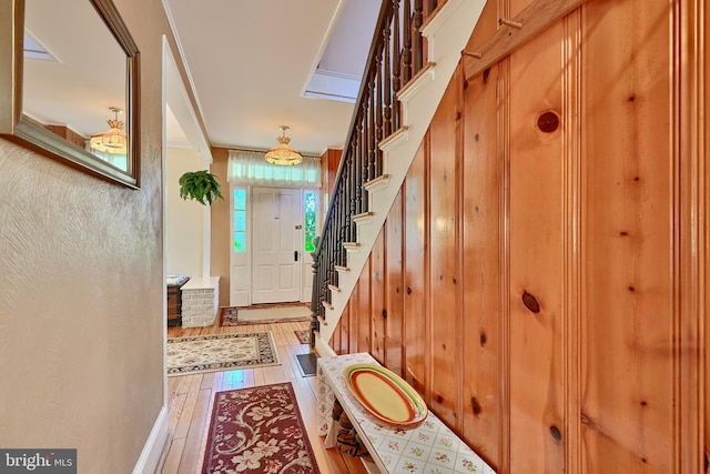 foyer entrance featuring ornamental molding, wood walls, and wood-type flooring