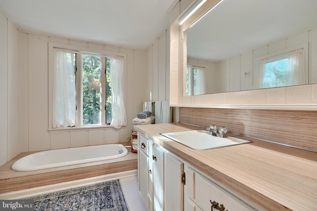 bathroom with tile patterned floors, a tub to relax in, and vanity