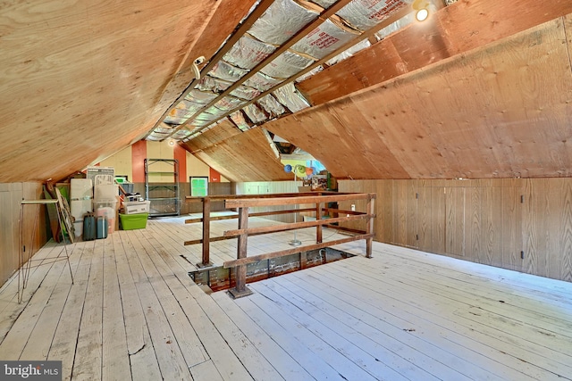 bonus room with lofted ceiling, wood walls, and light hardwood / wood-style flooring