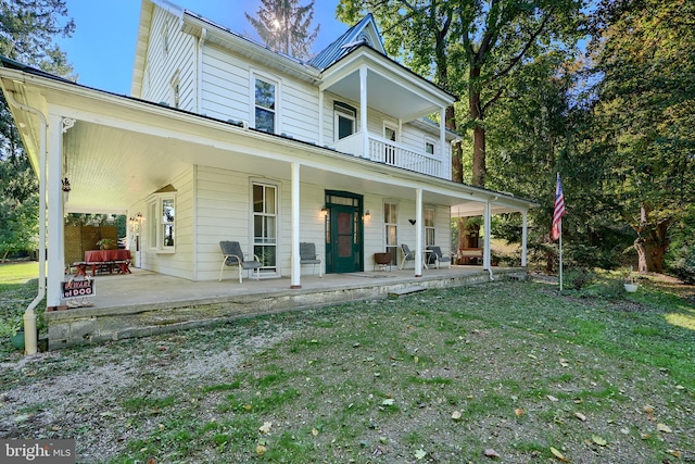 back of house featuring a porch, a balcony, and a lawn