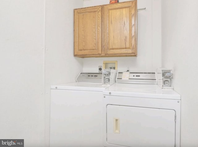 clothes washing area with washer and clothes dryer and cabinets