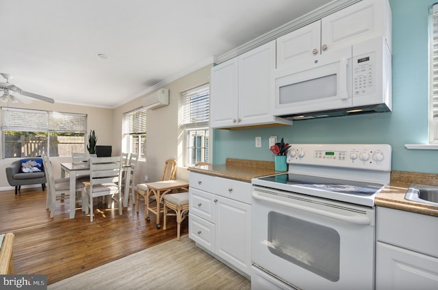 kitchen with white appliances, light hardwood / wood-style flooring, white cabinetry, crown molding, and an AC wall unit