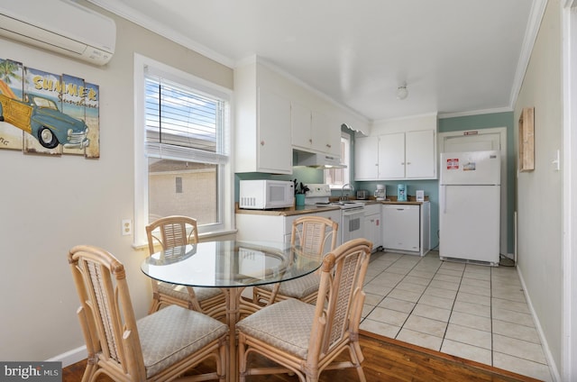 kitchen featuring white cabinets, white appliances, light wood-type flooring, crown molding, and a wall mounted air conditioner