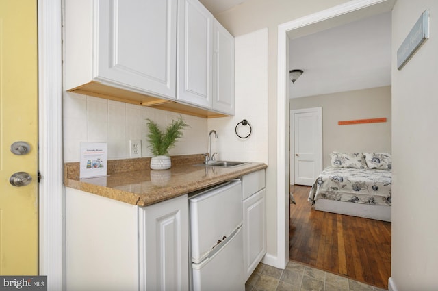 kitchen featuring decorative backsplash, white cabinets, sink, light hardwood / wood-style flooring, and dishwasher