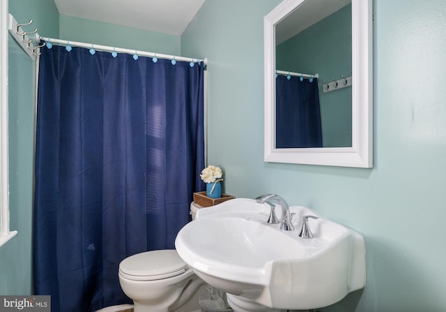 bathroom featuring sink, toilet, and a shower with shower curtain