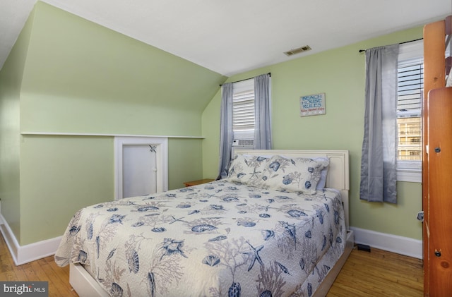 bedroom with lofted ceiling and light hardwood / wood-style floors