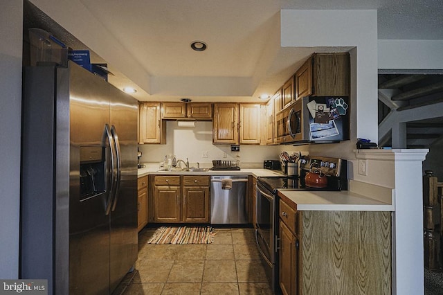 kitchen with light tile patterned floors, sink, appliances with stainless steel finishes, and a tray ceiling