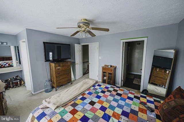 carpeted bedroom with ensuite bath, ceiling fan, and a textured ceiling