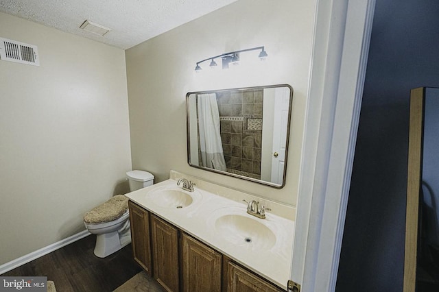 bathroom featuring hardwood / wood-style flooring, vanity, toilet, and a textured ceiling