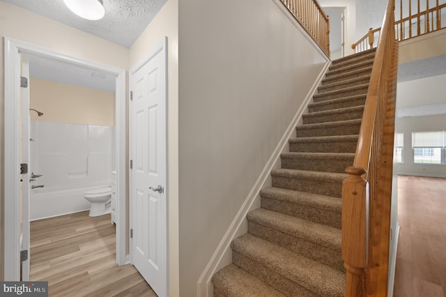 stairs with hardwood / wood-style floors and a textured ceiling