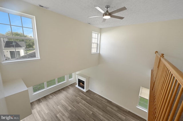 unfurnished living room featuring hardwood / wood-style floors, a textured ceiling, and ceiling fan