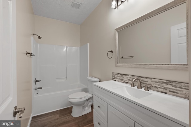 full bathroom featuring toilet, shower / tub combination, hardwood / wood-style floors, vanity, and a textured ceiling