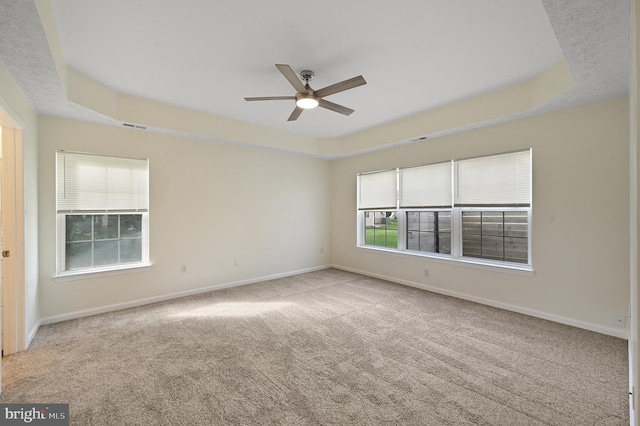 carpeted empty room featuring ceiling fan and a tray ceiling