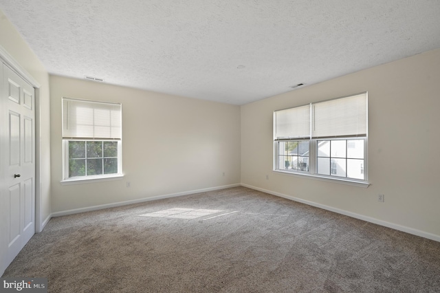 carpeted empty room with a textured ceiling